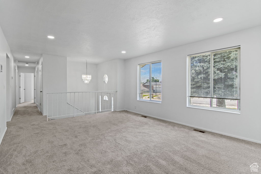 Carpeted spare room featuring a chandelier, recessed lighting, and baseboards