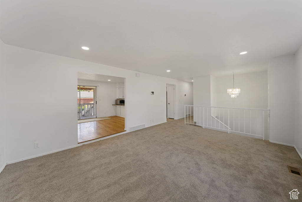 Empty room with carpet floors, recessed lighting, a chandelier, and baseboards