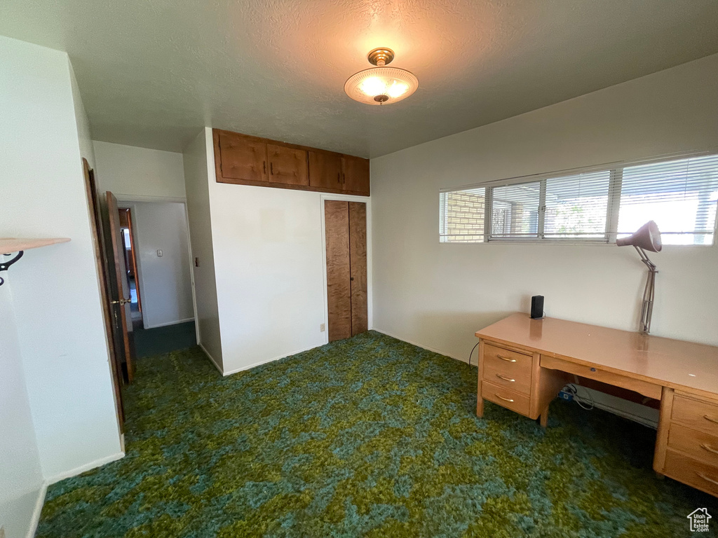 Home office featuring dark colored carpet