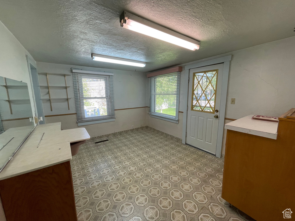 Doorway to outside featuring a textured ceiling and plenty of natural light