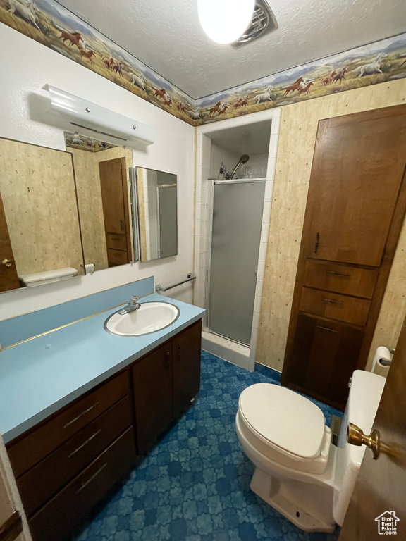 Full bath with a stall shower, tile patterned floors, a textured ceiling, vanity, and toilet