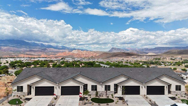 Ranch-style home with a mountain view, driveway, stucco siding, and an attached garage
