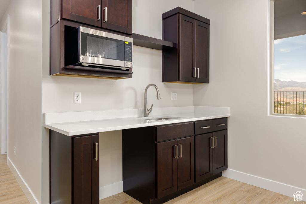 Kitchen featuring stainless steel microwave, a sink, light wood finished floors, and light countertops