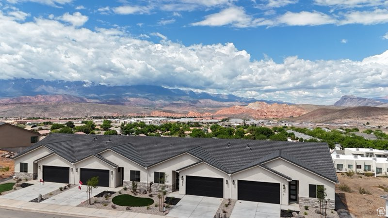 View of front of home with a mountain view, concrete driveway, stucco siding, and a garage