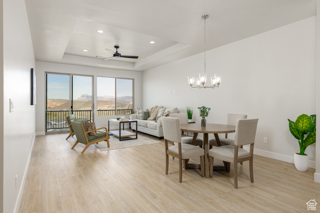 Dining space with light wood-style flooring, baseboards, a raised ceiling, a ceiling fan, and recessed lighting