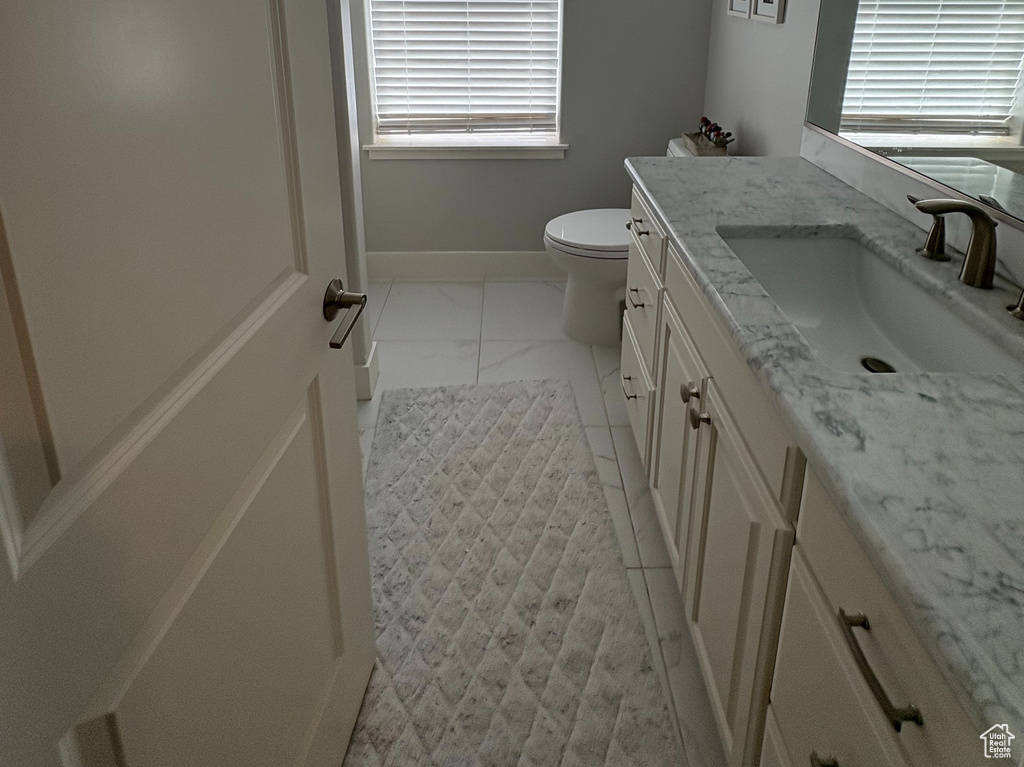 Bathroom with vanity, toilet, and marble finish floors