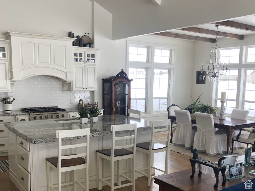 Kitchen featuring tasteful backsplash, beamed ceiling, dark wood-style flooring, and stone counters