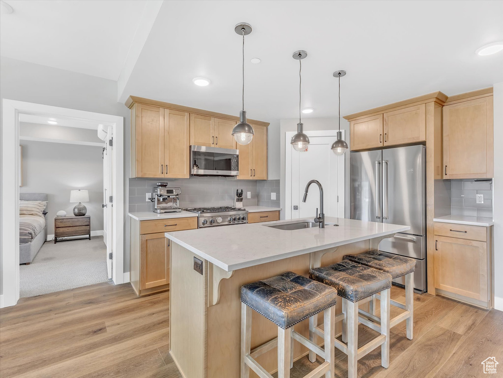 Kitchen with a sink, stainless steel appliances, light brown cabinetry, light wood finished floors, and recessed lighting