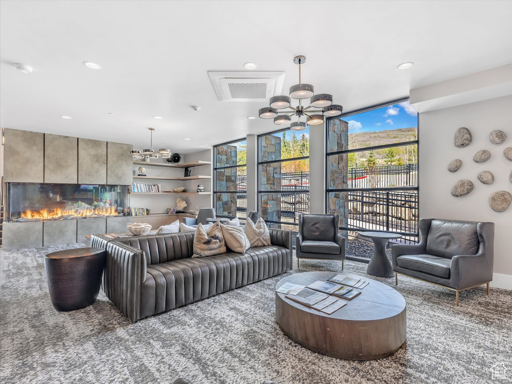 Living room featuring floor to ceiling windows, carpet flooring, recessed lighting, a fireplace, and a chandelier