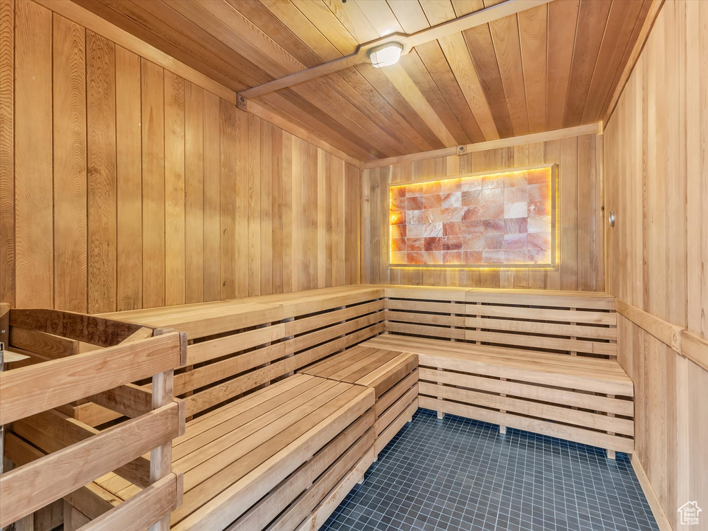 Sauna featuring wooden walls, wooden ceiling, and tile patterned flooring