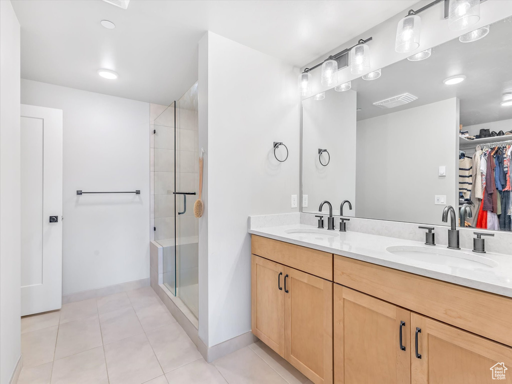 Full bathroom with tile patterned flooring, a spacious closet, baseboards, a shower stall, and double vanity