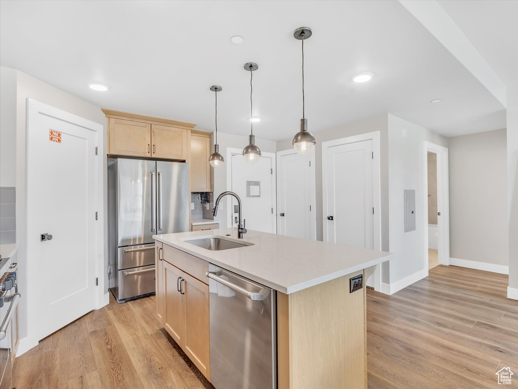 Kitchen with stainless steel appliances, light brown cabinets, a sink, light wood-style flooring, and light countertops