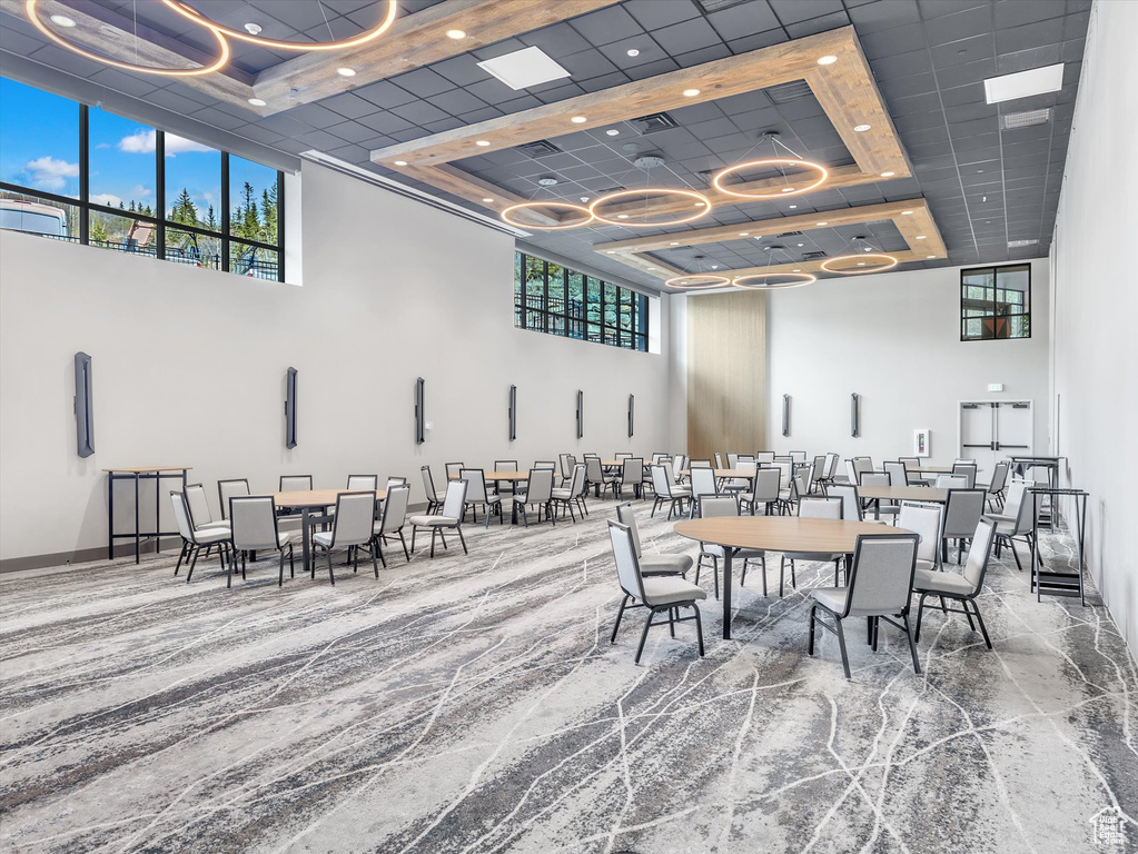 Carpeted dining room featuring a towering ceiling, a raised ceiling, recessed lighting, and baseboards