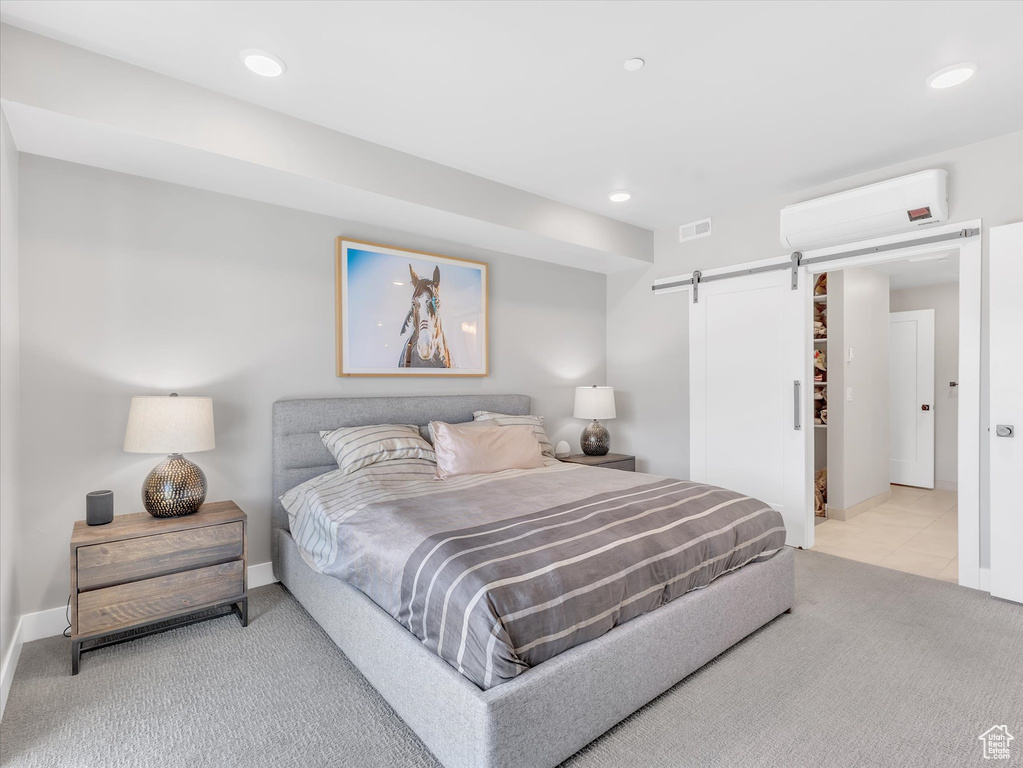 Carpeted bedroom with a wall mounted air conditioner, a barn door, recessed lighting, and baseboards