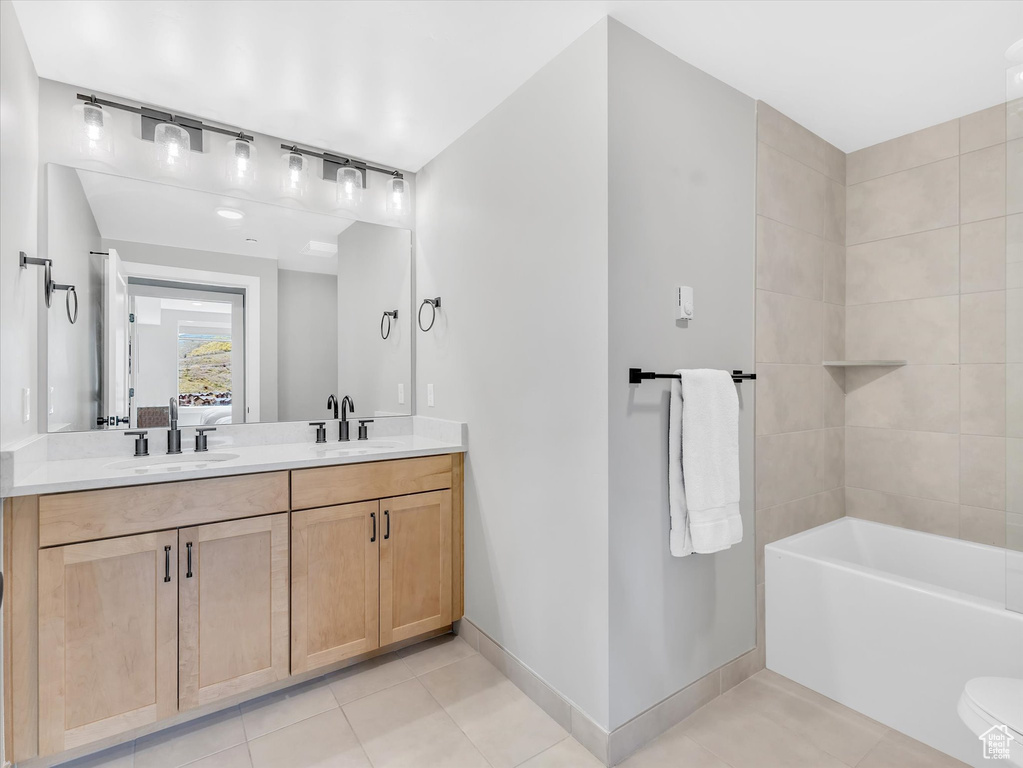 Full bathroom featuring tile patterned floors, baseboards, double vanity, and ensuite bath