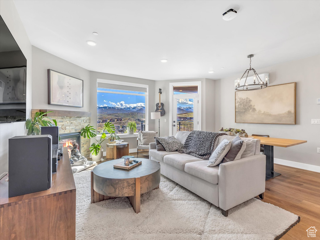 Living room with baseboards, wood finished floors, a fireplace, recessed lighting, and a chandelier