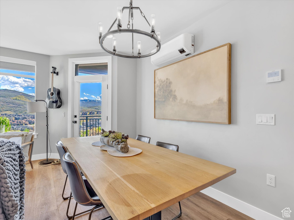 Dining room featuring a wall unit AC, a chandelier, light wood-style floors, and baseboards