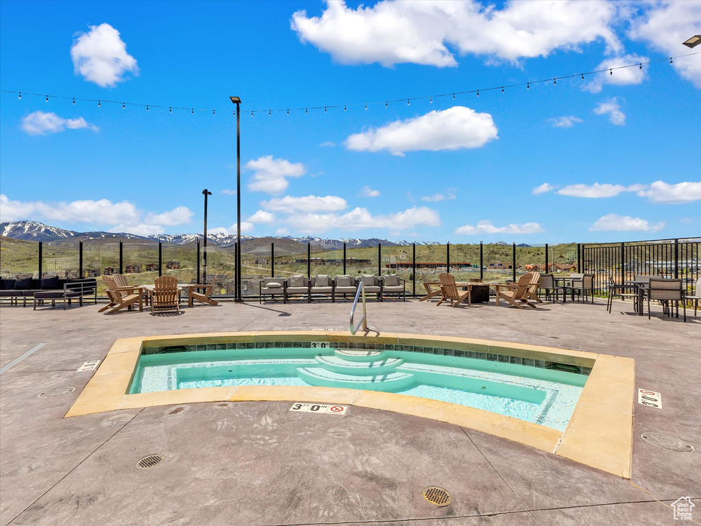 View of swimming pool with a mountain view, a patio, a hot tub, and fence