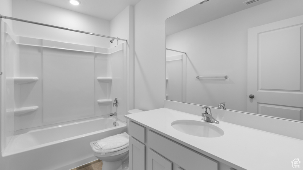 Bathroom featuring toilet, wood finished floors, vanity, washtub / shower combination, and recessed lighting