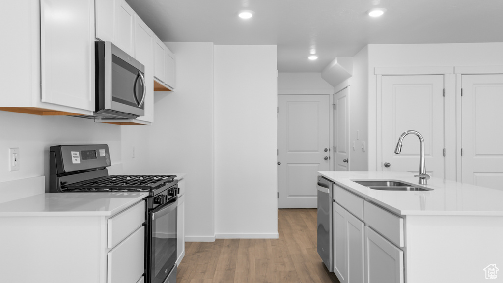 Kitchen featuring appliances with stainless steel finishes, a sink, light wood-style flooring, recessed lighting, and light countertops