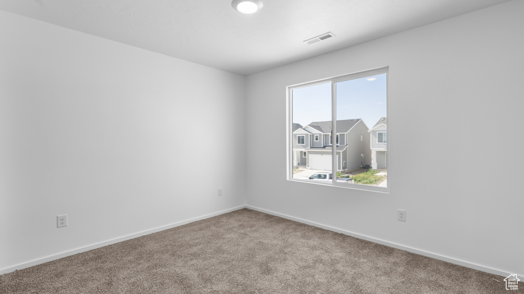 Carpeted spare room featuring baseboards