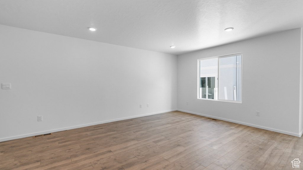 Unfurnished room with wood finished floors, baseboards, and recessed lighting