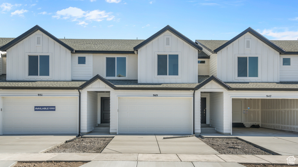 Townhome / multi-family property with board and batten siding, an attached garage, and a shingled roof