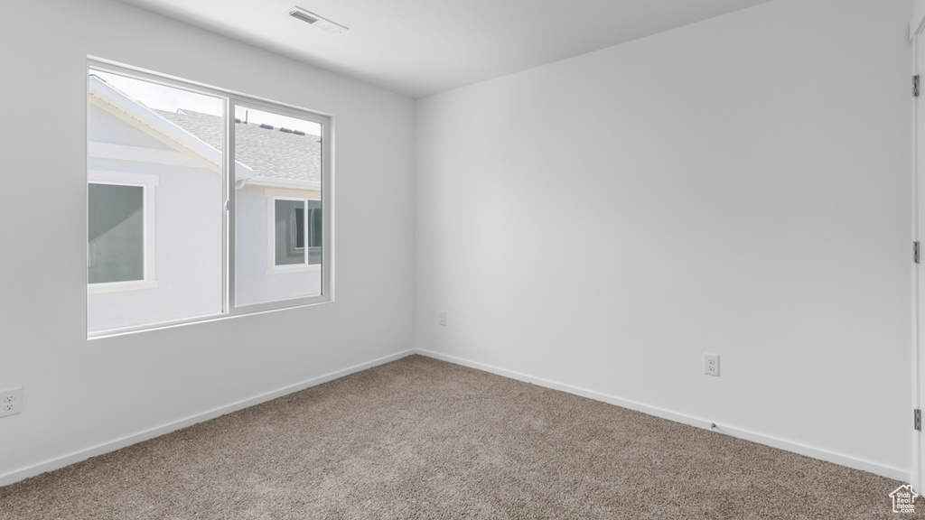 Carpeted spare room featuring baseboards