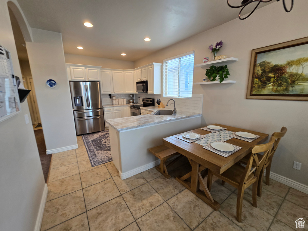 Kitchen with stainless steel appliances, a sink, white cabinetry, a peninsula, and arched walkways