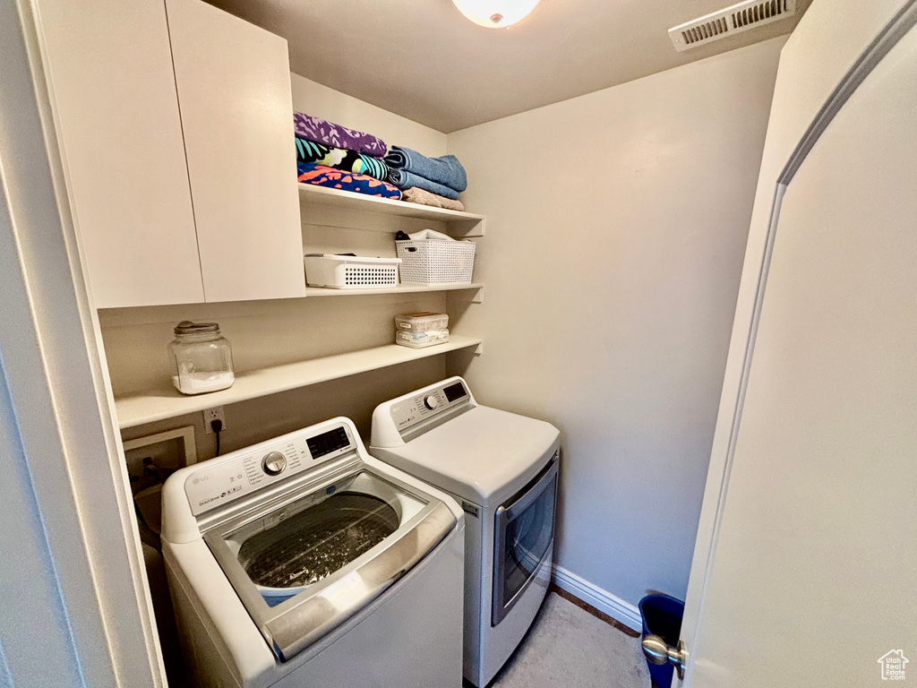 Laundry room featuring independent washer and dryer, baseboards, and light carpet