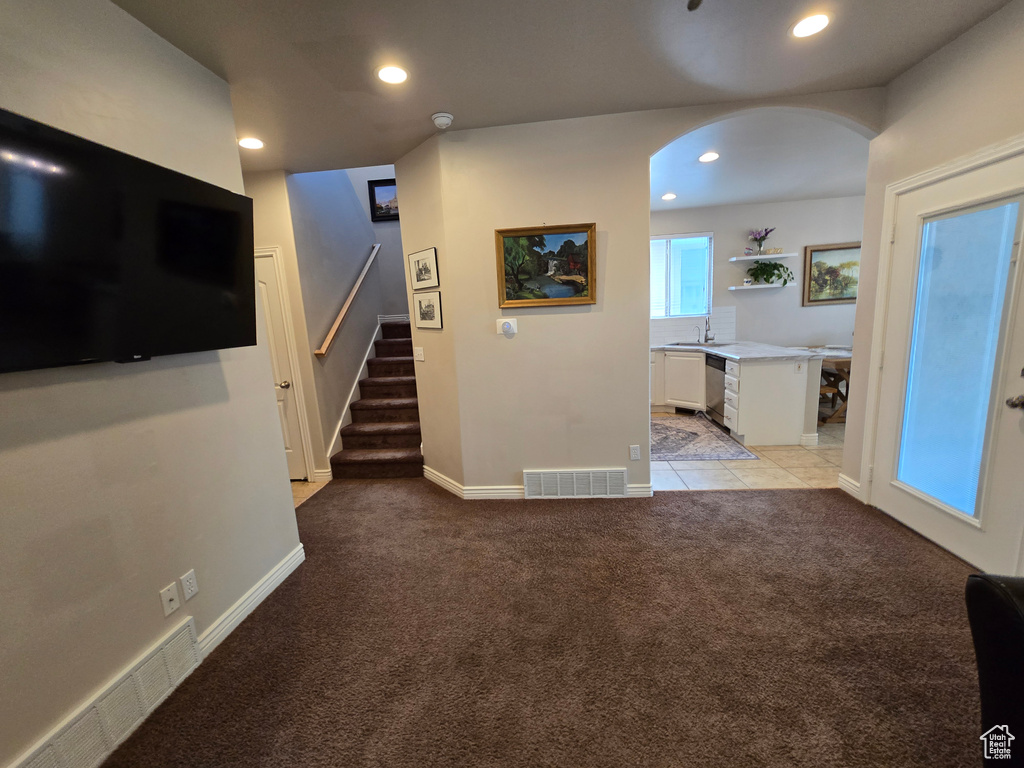 Unfurnished living room with light carpet, a sink, stairway, recessed lighting, and arched walkways