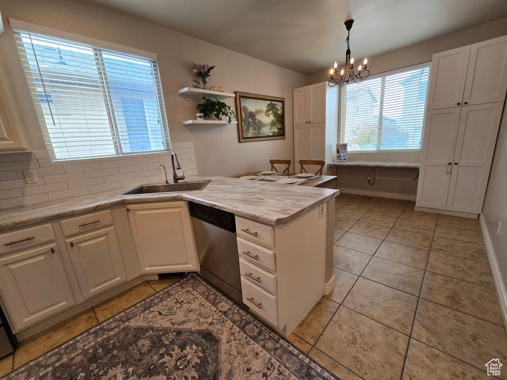 Kitchen with a sink, dishwasher, a peninsula, tasteful backsplash, and white cabinetry