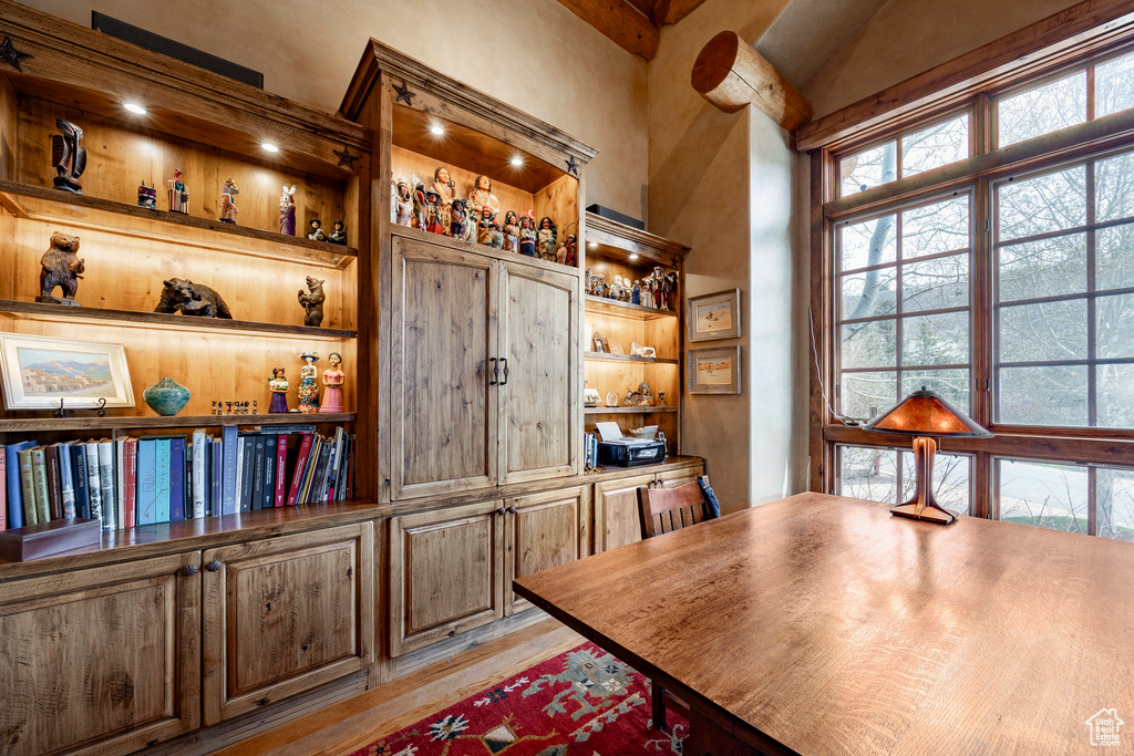 Dining area featuring built in features, light wood-type flooring, plenty of natural light, and a high ceiling