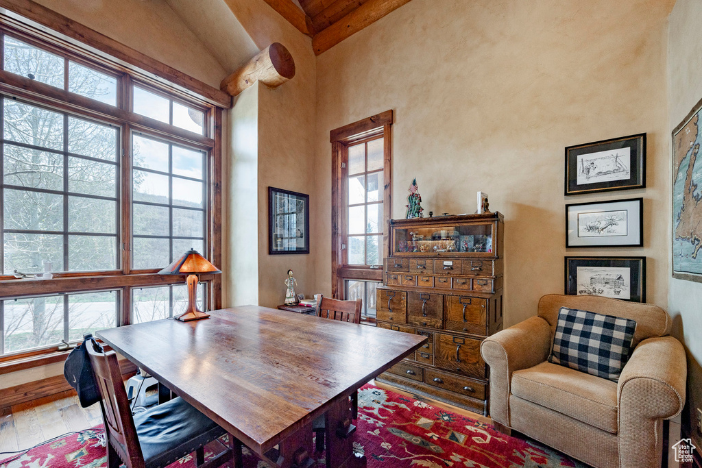 Dining space featuring beamed ceiling, a towering ceiling, and wood-type flooring