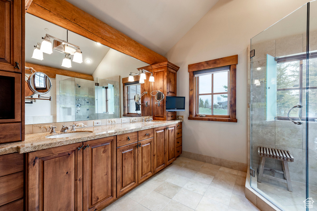 Full bath with vaulted ceiling, a stall shower, double vanity, tile patterned flooring, and baseboards