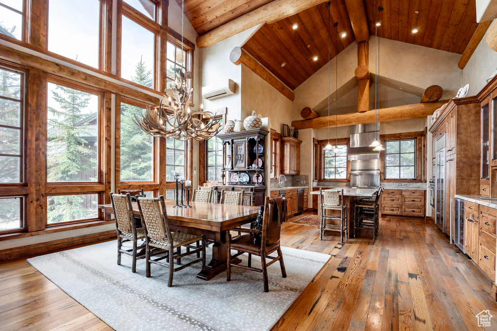 Dining room with high vaulted ceiling, light wood finished floors, a wall mounted AC, wine cooler, and a chandelier