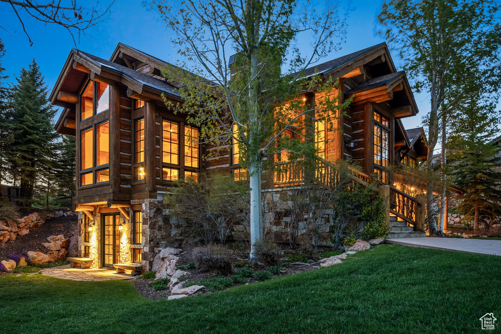 View of home's exterior featuring a lawn, a chimney, stairs, and log exterior
