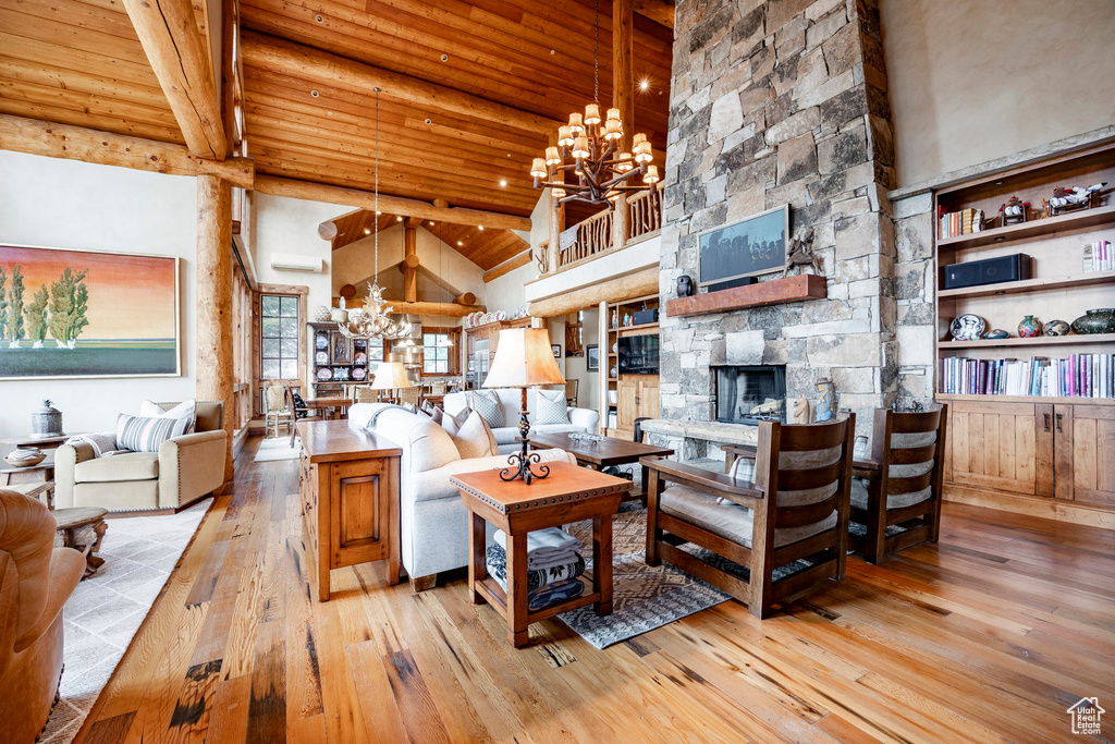 Living area with a chandelier, wood-type flooring, a stone fireplace, wooden ceiling, and high vaulted ceiling