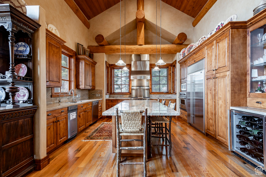 Kitchen with wine cooler, built in appliances, wooden ceiling, a sink, and light wood finished floors