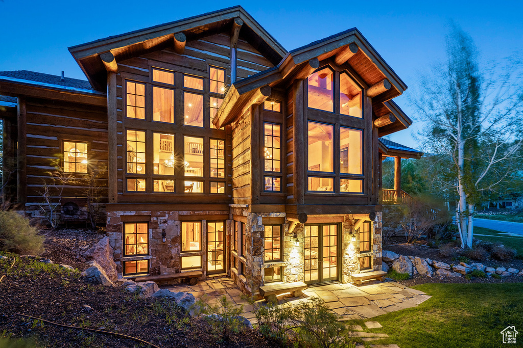 Back of house featuring stone siding and a patio