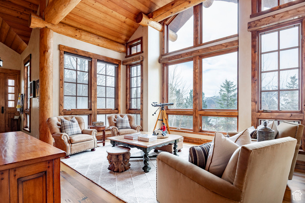 Living room with wood finished floors, healthy amount of natural light, wooden ceiling, beam ceiling, and high vaulted ceiling