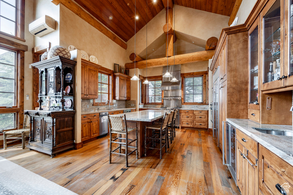 Kitchen featuring a sink, a kitchen bar, brown cabinetry, high vaulted ceiling, and light wood finished floors