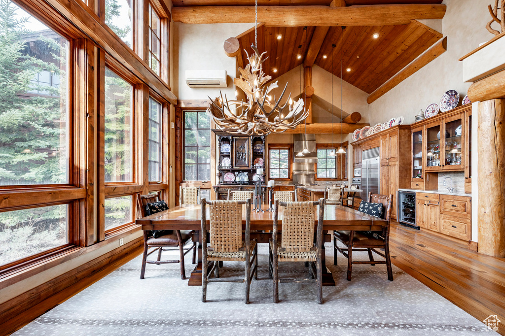 Dining room with beverage cooler, high vaulted ceiling, a chandelier, wood finished floors, and a wall mounted AC