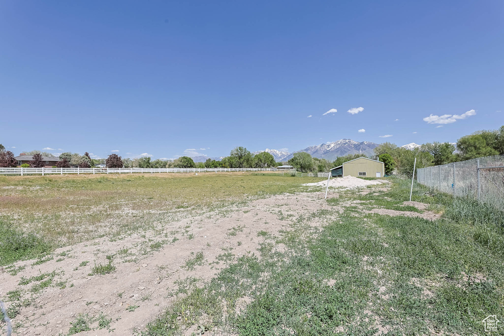 View of yard with fence, a rural view, and a mountain view