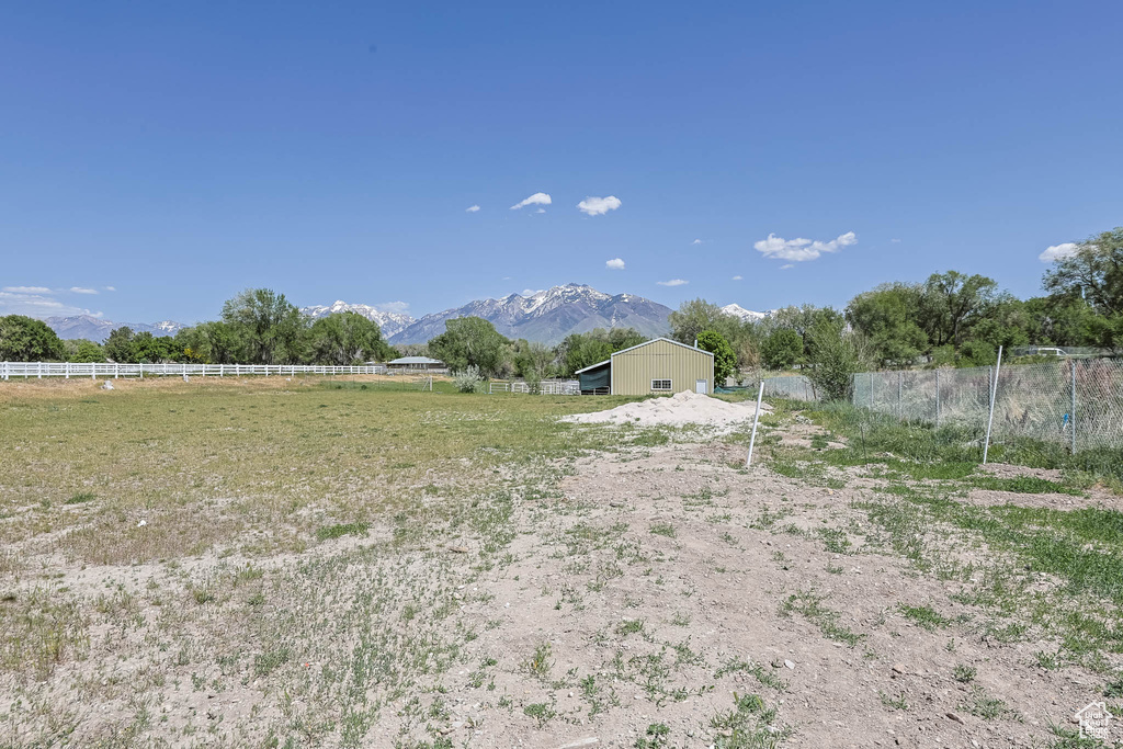 View of yard with fence, an outbuilding, a rural view, and a mountain view