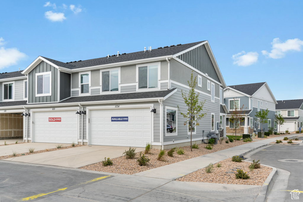 View of front of house featuring board and batten siding, an attached garage, driveway, and a residential view