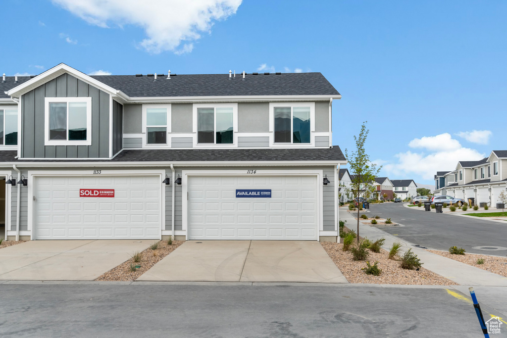 Multi unit property featuring driveway, an attached garage, a residential view, board and batten siding, and roof with shingles