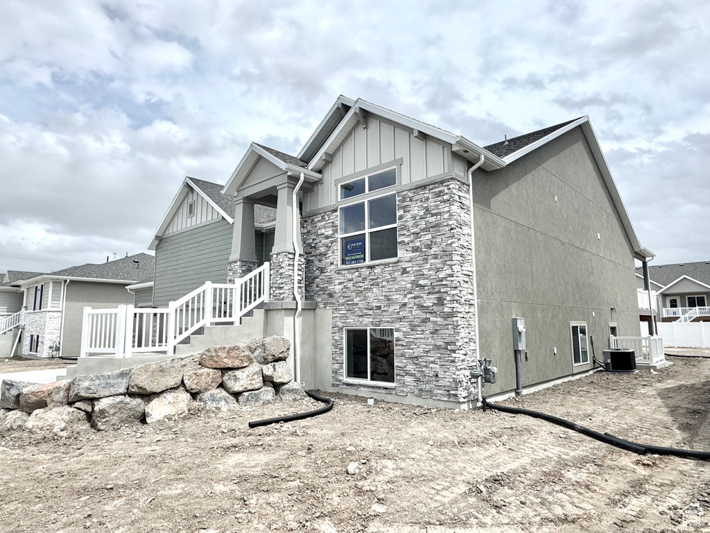 View of home's exterior with stone siding, board and batten siding, and central AC unit