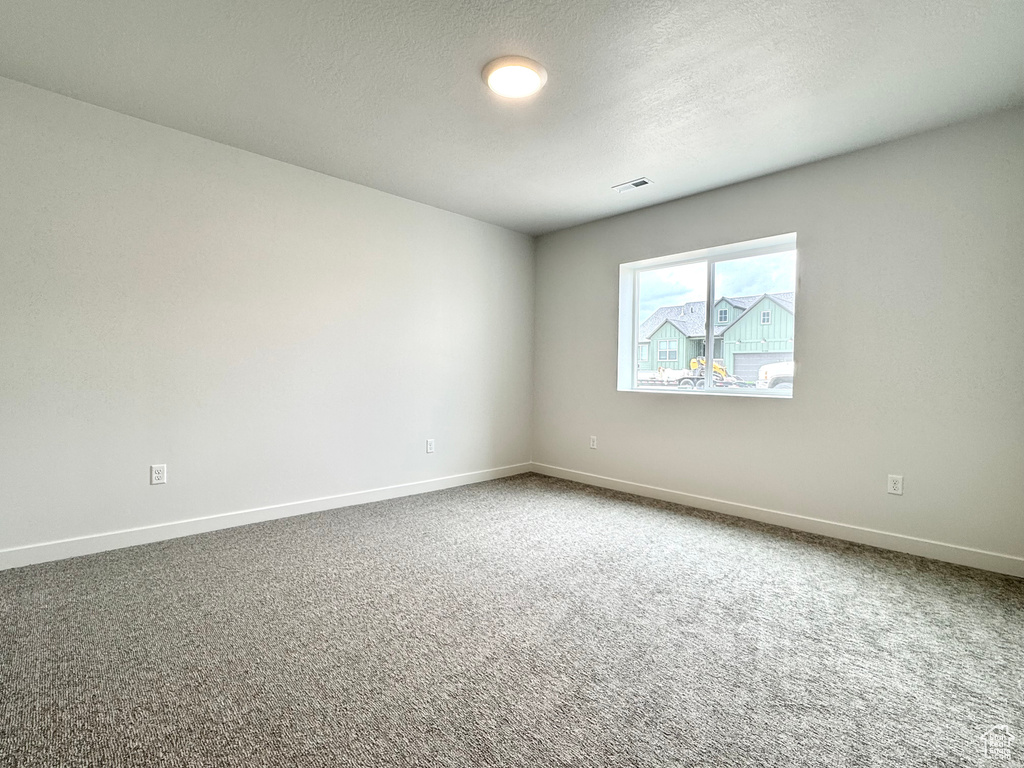 Empty room with baseboards, carpet, and a textured ceiling