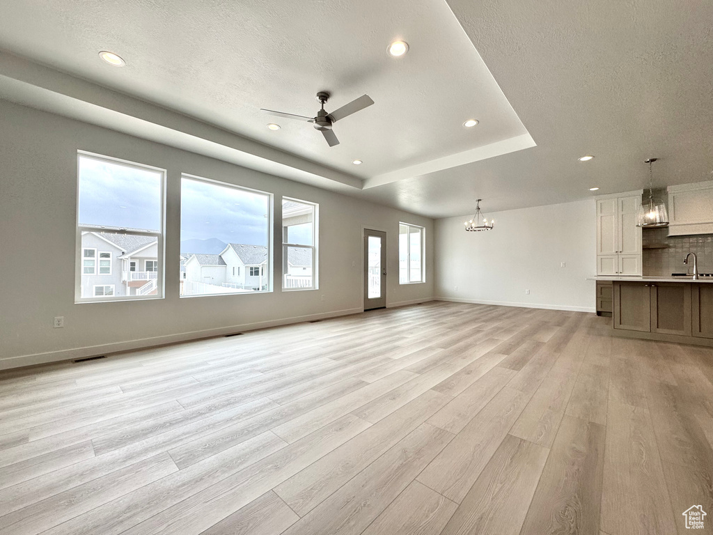 Unfurnished living room with a sink, a chandelier, light wood-type flooring, recessed lighting, and a ceiling fan